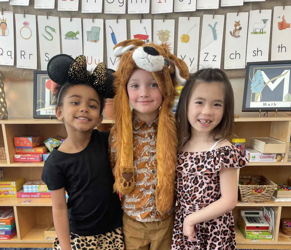 Preschool students smiling in animal print costumes for a themed dress-up day in their classroom.